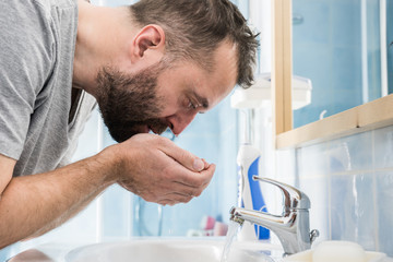 Man washing his face in bathroom