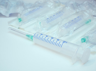 close-up of one syringe with attached needle and pack of syringes on background. pharmacy drug store banner