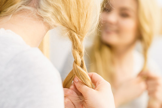 Woman making braid on blonde hair