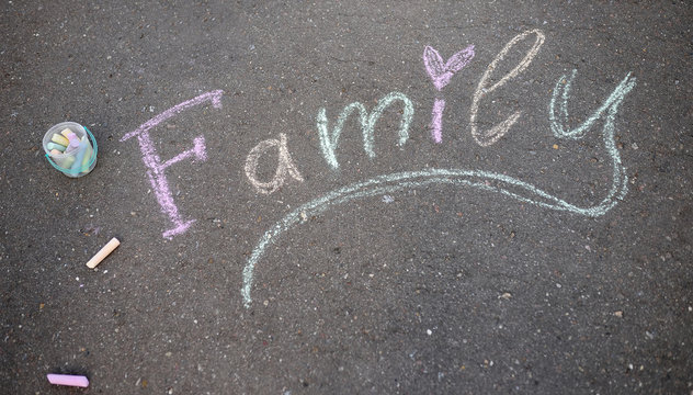 The word "family" painted with colored chalk on asphalt
