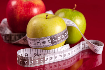 Yellow  Apples with measuring tape on red background. Weight loss concept