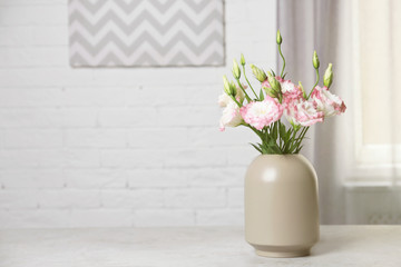 Beautiful flowers in vase and space for text on blurred background. Element of interior design