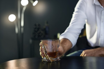 Man holding glass with whiskey at table, closeup. Space for text