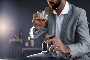 Man with glass of whiskey and cigar sitting at table, closeup. Space for text
