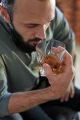 Handsome man holding glass of whiskey indoors