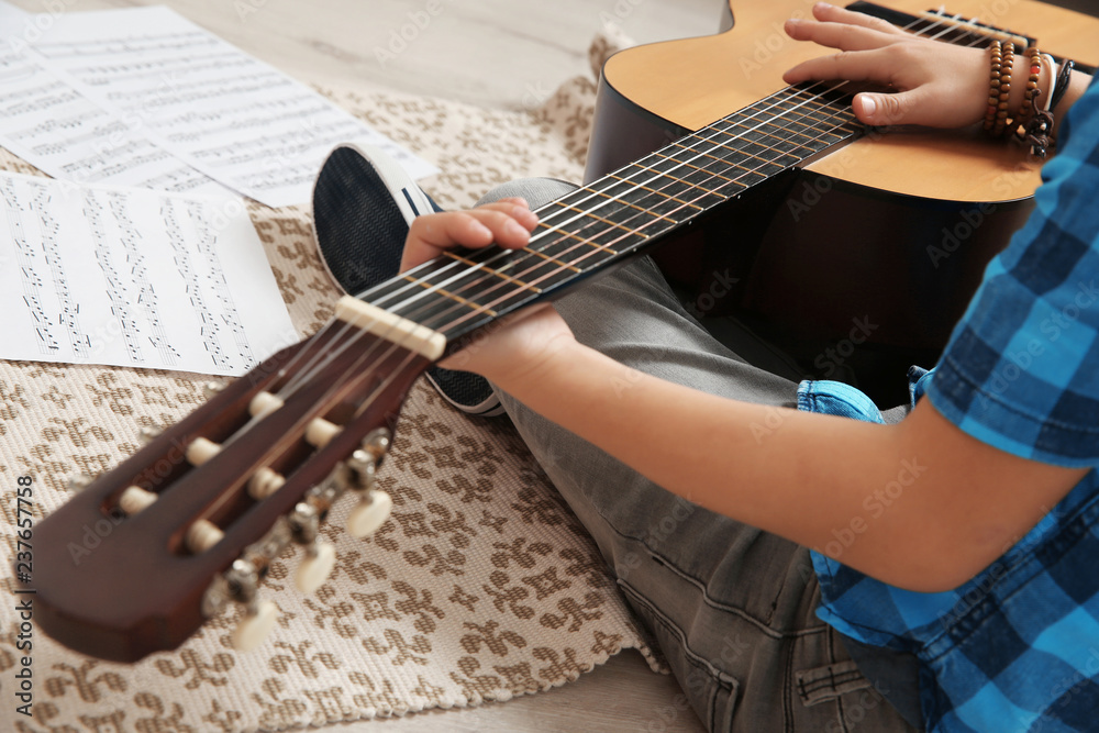 Poster Little boy playing guitar on floor, closeup