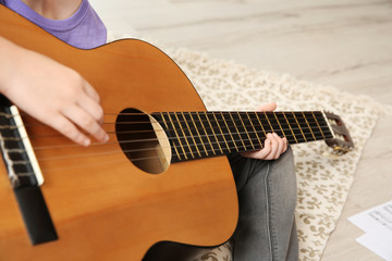 Little girl playing guitar on floor, closeup