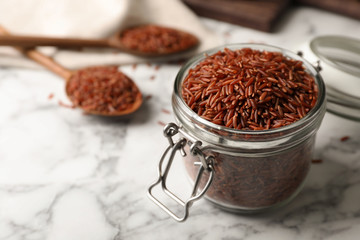 Brown rice in glass jar on table. Space for text