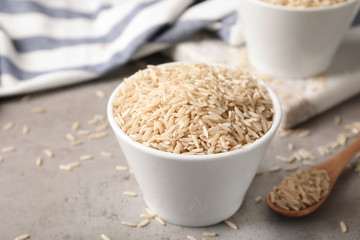 Uncooked brown rice in small bowl on table. Space for text