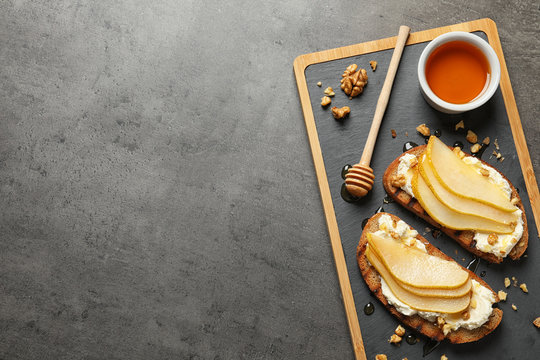 Toasted bread with tasty cream cheese and pear on gray table, flat lay. Space for text