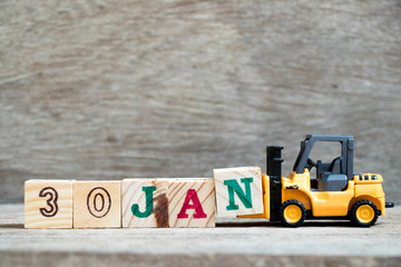 Toy forklift hold block N to complete word 30jan on wood background (Concept for calendar date in 30 month January)