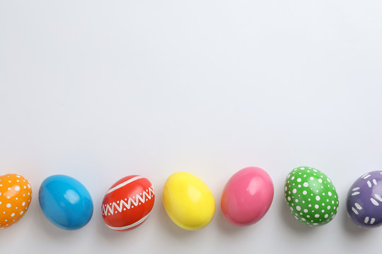 Decorated Easter eggs and space for text on white background, top view