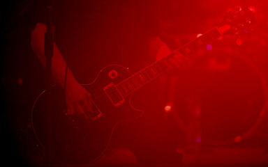 Close up scene of electric guitar player on performing stage during playing solo on concert with colourful scenic illumination via powerful lights. Unicolor simple photography