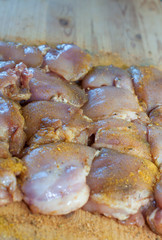 Raw chicken breasts and spices on wooden cutting board, top view with free text space