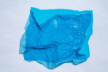 Thin sheet of blue colour cellophane with shiny crumpled surface texture  on white background,...