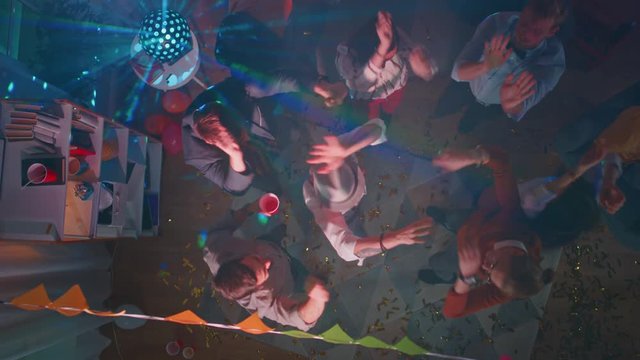 At the College Party: Diverse Group of Friends Have Fun, Dance, Socialize and Drink. Stylish Young People Dance Energetically in the Living Room. Disco Neon Lights. Top Down Shot.