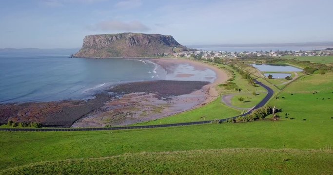 Amazing aerial flight over green field away from rock in Tasmania, Australia