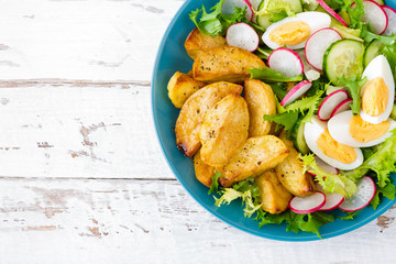 Delicious baked potato, boiled egg and fresh vegetable salad of lettuce, cucumber and radish. Summer menu for detox diet