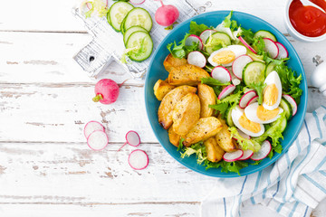 Delicious baked potato, boiled egg and fresh vegetable salad of lettuce, cucumber and radish. Summer menu for detox diet