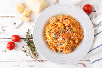 Spaghetti bolognese pasta with tomato sauce, vegetables and chicken meat on white wooden rustic background. Traditional italian food. Top view. Flat lay