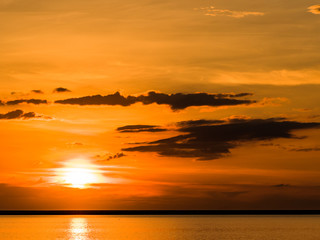 Sunset across the ocean with orange sky and island silhouettes on the horizon