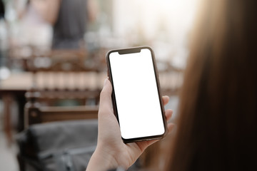 close-up on hand holding phone showing white screen on desk at coffee shop.