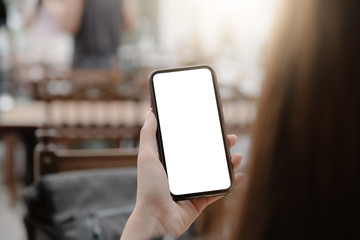 close-up on hand holding phone showing white screen on desk at coffee shop.