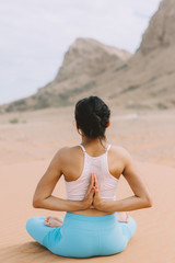 Fototapeta na wymiar Young woman doing yoga in desert with mountains at sunrise time