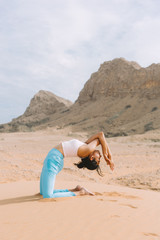 Young woman doing yoga in desert with mountains at sunrise time