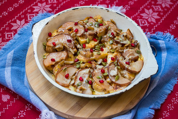 Baked fruits baked in cast iron skillet pan with apples, pears, pomegranate grains, bananas, nuts, pumpkin seeds, natural honey.