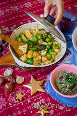 Christmas lunch, dinner food. Baked, roasted or grilled vegetables in cast iron skillet. Brussels sprout, cauliflower. Woman hands holds vegetarian food