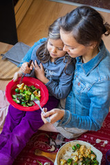 Christmas lunch, dinner food. Baked, roasted or grilled vegetables in cast iron skillet. Brussels sprout, cauliflower. Family of daughter (little girl) and mother (young woman) together eats food