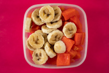 Fruits in a bowl on a pink background.