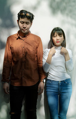 portrait of asian younger man and woman like fashion model standing against beautiful light wall