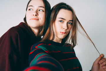 Two sisters twins beautiful girls in casual taking selfie on fro