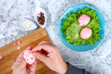 Diy pig from eggs. Workshop how to make a pig from a boiled egg painted in broth beets stuffed with stuffing. Appetizer on Christmas or New Year table. Top view. Creative decorative food for kid.