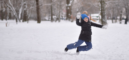 Fototapeta na wymiar a child in winter clothes jumping on the snow