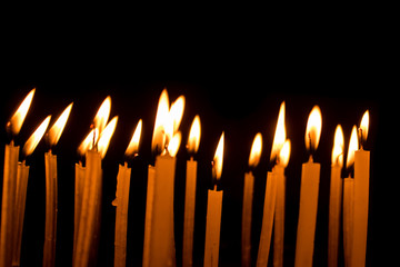 Many christmas candles burning at night on the black background.