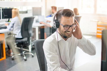 Happy young male customer support executive working in office.