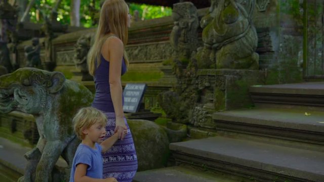 Slowmotion shot of a young woman and her little son visiting the Monkeys forest eco park in Ubud, Indonesia