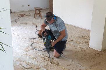 Construction concept - Jackhammer, removing chipboard from the floor