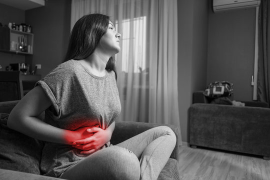 young woman has pain in right hypochondrium, young woman has a stomachache, black and white photo, red accent, gallbladder disease