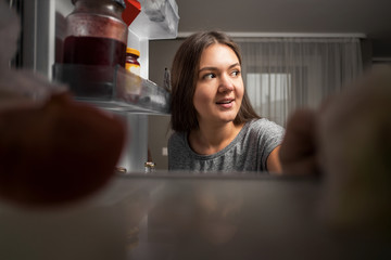young woman looks into the fridge, view from fridge, girl eating at night, fears