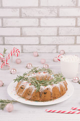 Traditional Christmas fruit cake on a white wooden table. Homemade pudding with festive decorations, candy canes