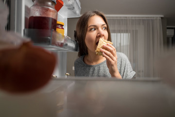 young woman looks into the fridge, view from fridge, girl eating at night, fears