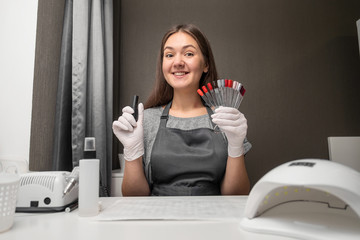 happy  young woman profession manicurist with polish and nail color palette