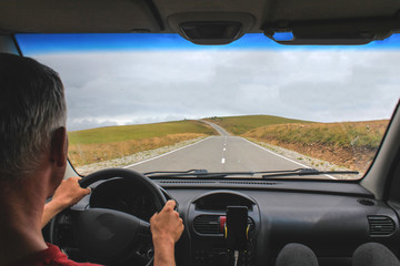 Man Man holding the steering wheel driving a car or truck on a rural road through the mountainsholding the steering wheel driving a car or truck on a rural road through the mountains