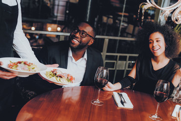 Waiter Serving Salad to African Couple Restaurant