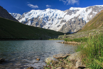 View of the alpine lake and snowy peaks. Main Caucasian ridge. Highland Caucasian reserve.
