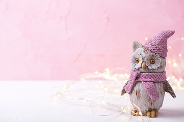 Decorative toy bird owl and fairy lights on bright  pink wooden  background.